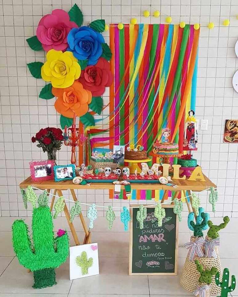 58. Você pode criar os seus próprios enfeites como cortina de fitas e painel de flores de papel para a decoração de festa mexicana – Foto: Mila Omena