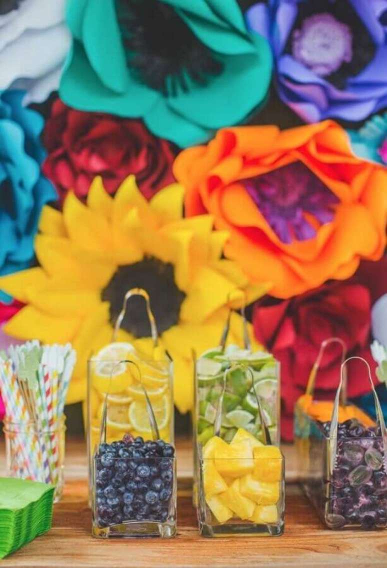 59. Painel de flores de papel coloridas e jarros com frutas e canudos coloridos para festa mexicana – Foto: My Sweet Decor