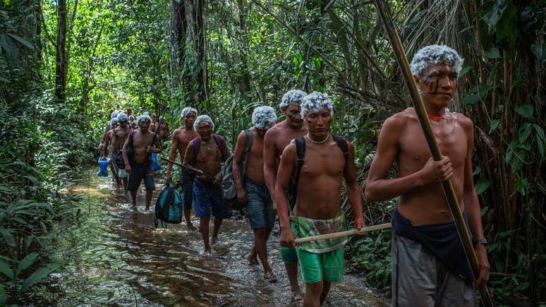 Guerreiros Yanomami cruzam riacho durante um encontro de lideran&ccedil;as na comunidade watoriki, na Terra Ind&iacute;gena Yanomami, em novembro de 2019