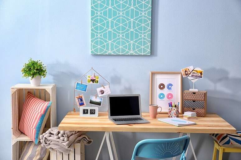 2. Home office com parede azul, objetos decorativos e vasinho de planta – Fonte: Shutterstock
