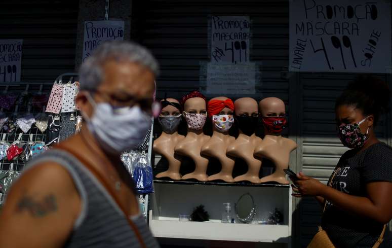 People wearing protective face masks walk past a street stall offering face masks, following the coronavirus disease (COVID-19) outbreak, in Rio de Janeiro, Brazil, May 5, 2020.  REUTERS/Pilar Olivares