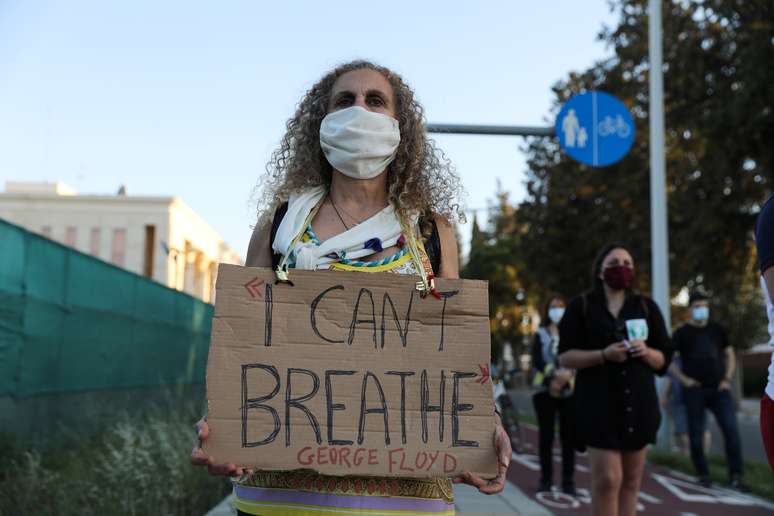 Manifestante usando máscara de proteção mostra cartaz protestando contra morte de  George Floyd, que estava sob custódia da polícia. 5/6/2020. REUTERS/Yiannis Kourtoglou