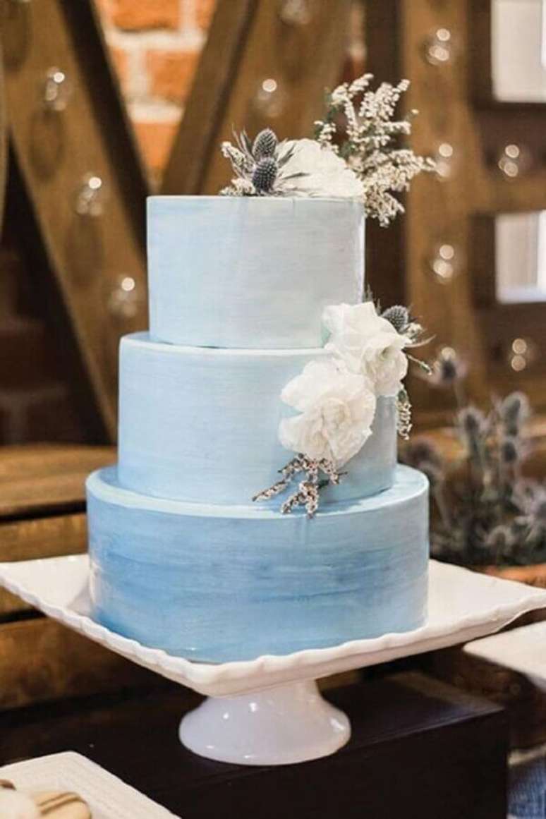 29. Decora&ccedil;&atilde;o de casamento azul com bolo 3 andares decorado com flores &ndash; Foto: Pinterest
