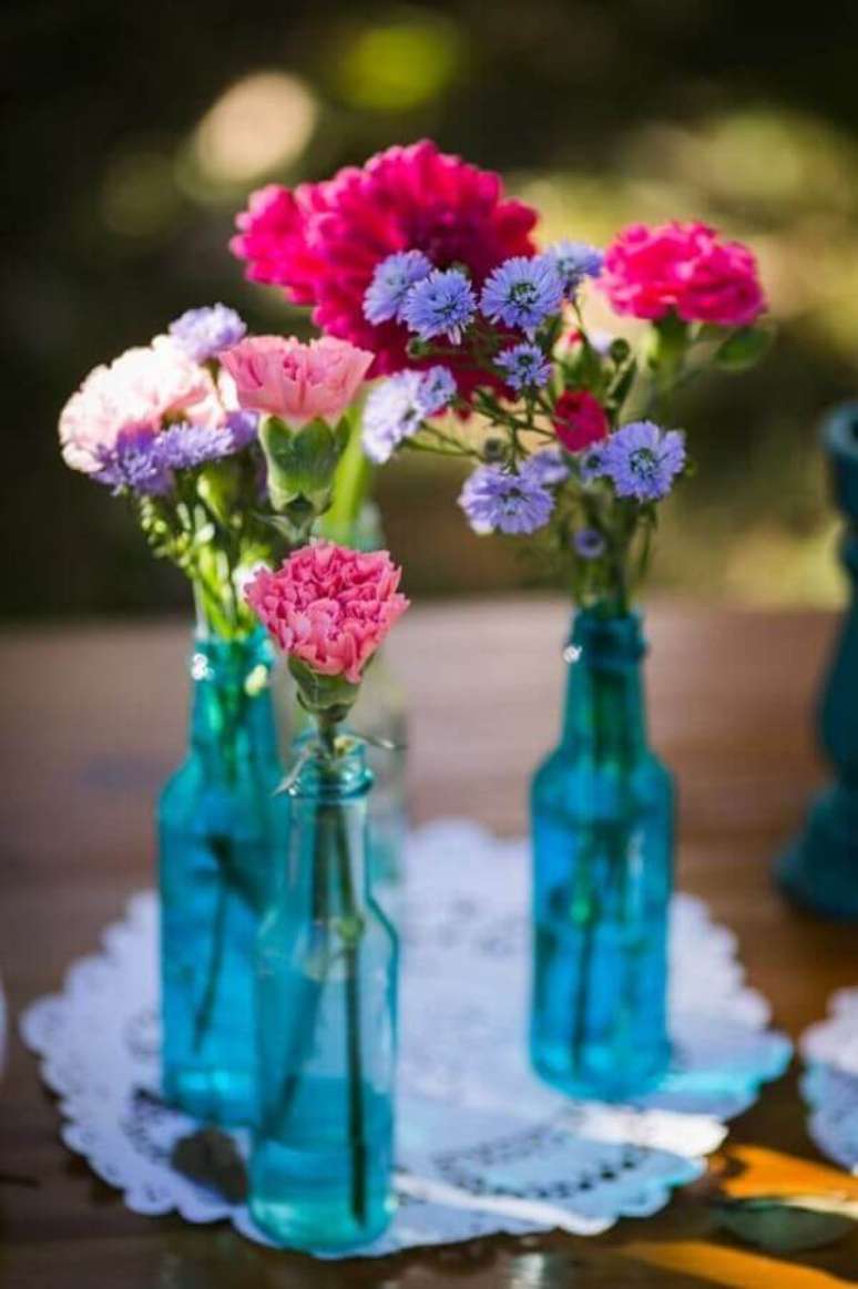53. Arranjos de flores simples dentro de garrafas de vidro para decoração de casamento azul simples – Foto: Casamento sem Segredo