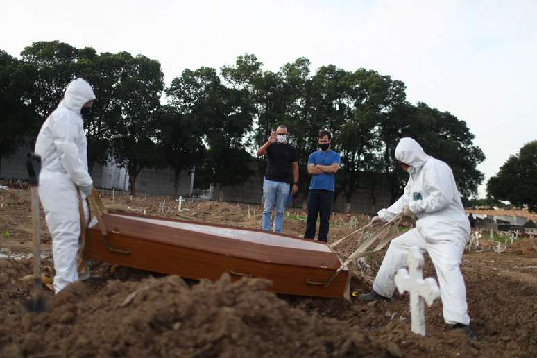 Irmãos Carlos Alexandre e Wagner Cardninot participam de enterro do pai, José Hermínio de Farias, de 76 anos, morto por Covid-19, no Rio de Janeiro.
REUTERS/Pilar Olivares