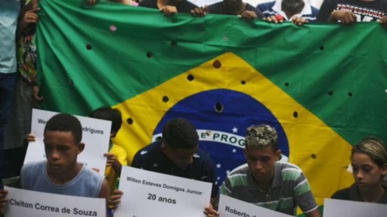 Bandeira do Brasil com buracos representa tiros de 111 balas disparadas contra 5 jovens no Rio, em 2015