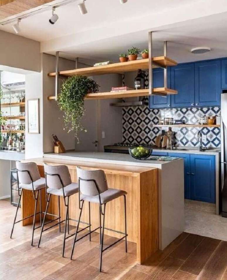 44. Prateleira suspensa cozinha planejada com armários azuis e bancada de madeira – Foto: Arkpad
