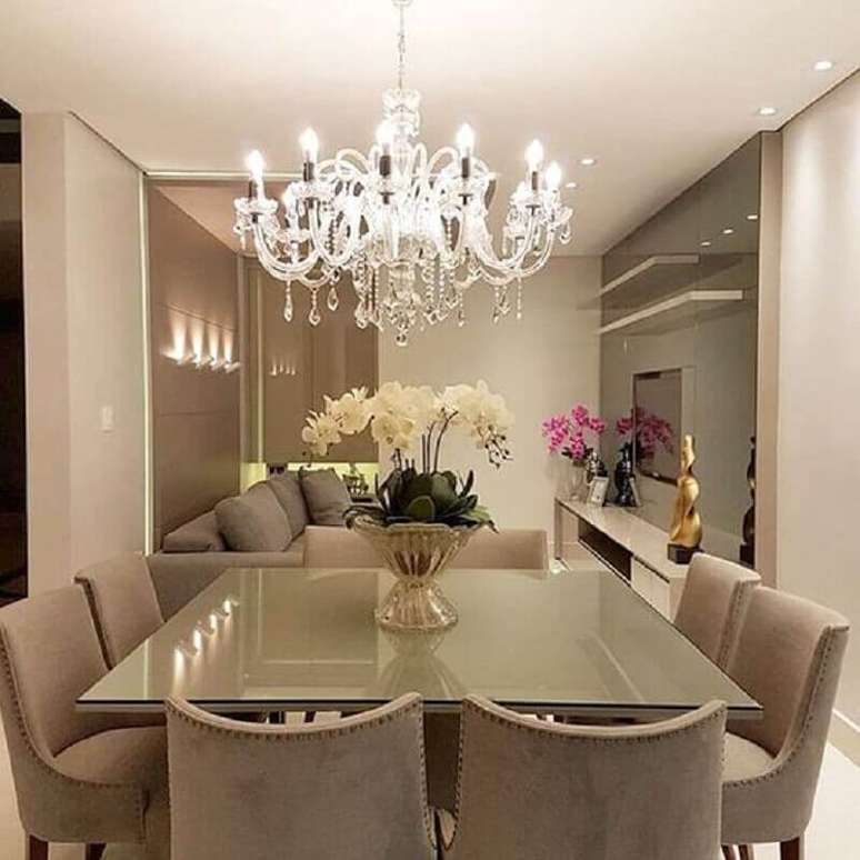 24. Decoração sofisticada com lustre de cristal e vaso de flor para mesa de jantar com acabamento em prata – Foto: We Love It