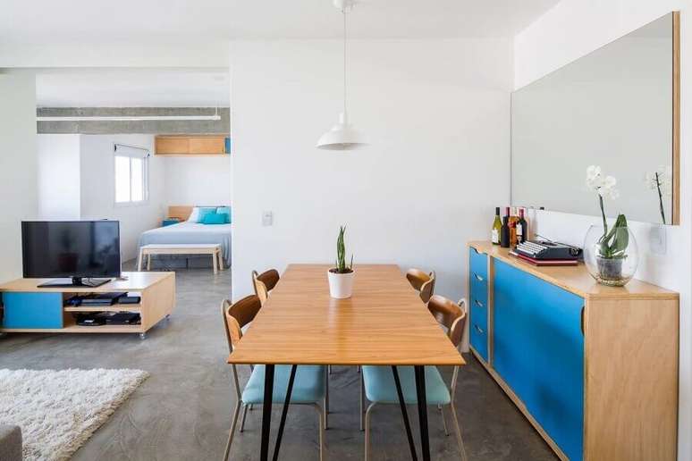 42. Sala de jantar simples decorada com móveis de madeira e detalhes em azul – Foto: Marco Zero Estúdio