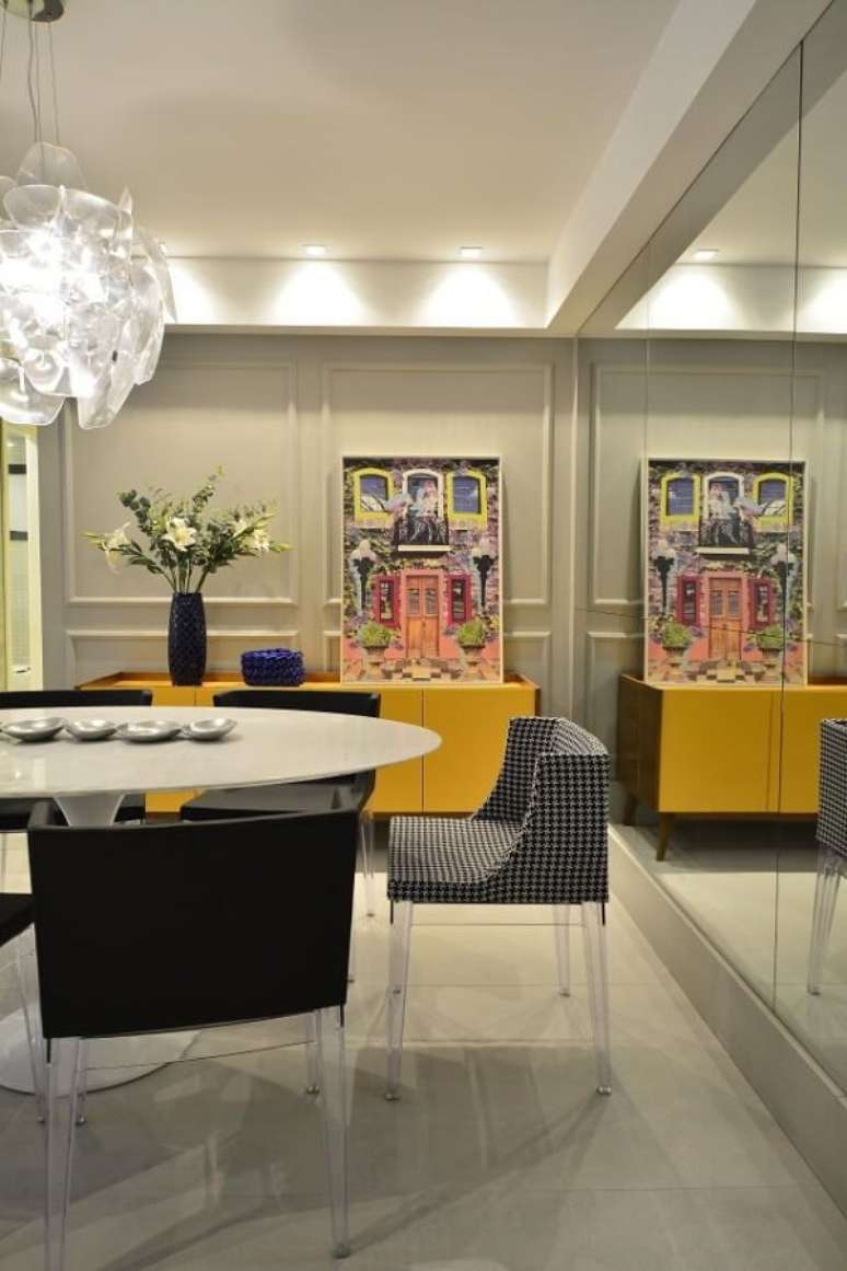 1. Parede espelhada e aparador buffet amarelo decoram a sala de jantar. Projeto por BG Arquitetura