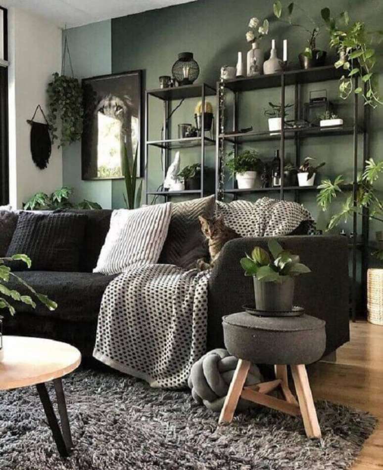35. Decoração de sala verde escura com sofá preto e vários vasos de plantas – Foto: Homedit