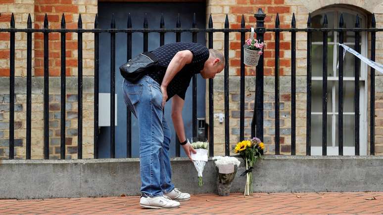Um homem colocando um tributo com flores em Reading, sul da Inglaterra