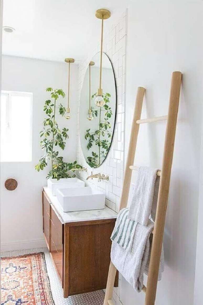 25. Decoração com plantas no banheiro clean com gabinete de madeira e pendente dourado – Foto: Pinterest