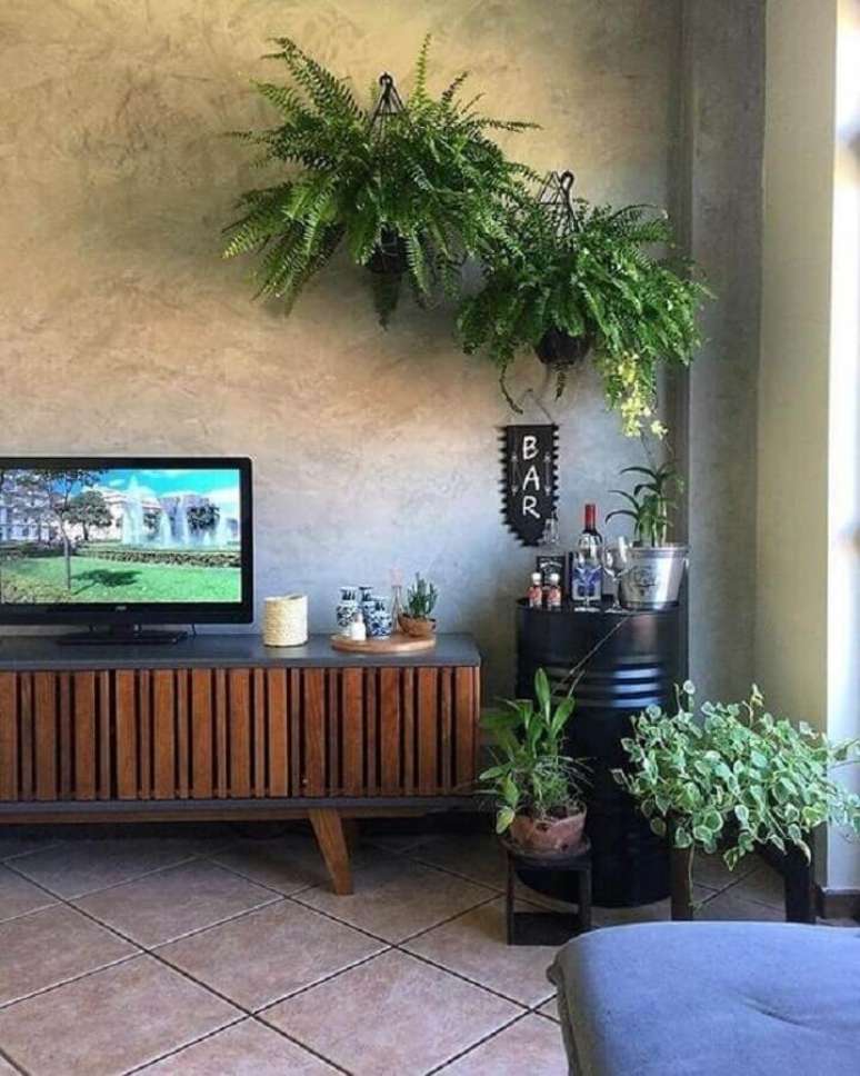 48. Decoração com plantas pendentes e vasos para sala moderna com tonel preto para barzinho e rack de madeira – Foto: Ideias de Casa