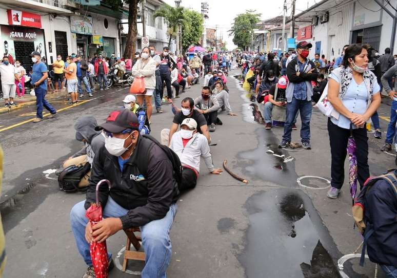 Pessoas fazem fila do lado de fora de um banco para receber auxílio do governo na cidade de Iquitos