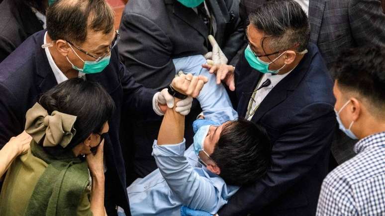 Um parlamentar é detido por guardas no Conselho Legislativo de Hong Kong durante um conflito sobre um projeto de lei sobre o hino nacional