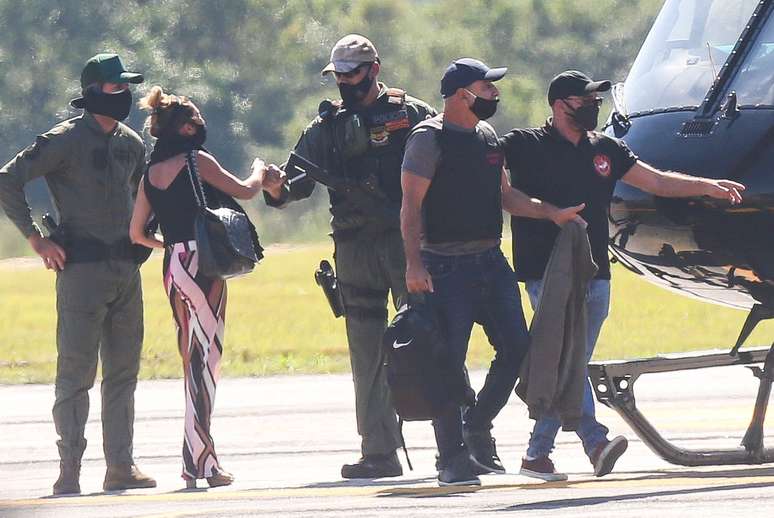 Cercado por policiais, Fabrício Queiroz (2º/d), ex-assessor do agora senador Flávio Bolsonaro (Republicanos-RJ), desembarca de helicóptero no Aeroporto de Jacarepaguá, na zona oeste do Rio de Janeiro