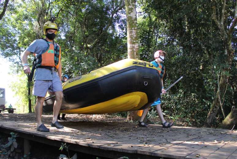 Turistas levam bote para a prática de rafting usando máscaras contra o coronavírus, em Brotas, no interior de São Paulo.