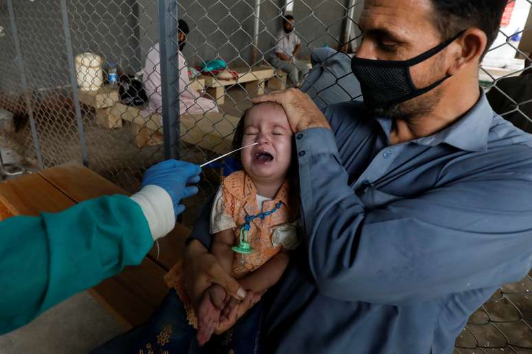 Paramédico em trajes de proteção coleta amostra de bebê para exame de detecçã de  Covid-19 em Karachi, no Paquistão
13/07/2020 REUTERS/Akhtar Soomro