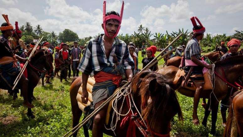 Homens sumbaneses montando seus cavalos no Festival de Pasola - uma religião animista é amplamente praticada na ilha