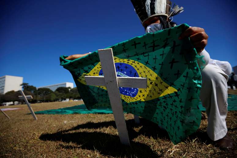 Ativista coloca bandeira do Brasil pintada com cruzes sobre cruz durante ato em homenagem a vítimas da Covid-19 em Brasília
14/07/2020
REUTERS/Adriano Machado