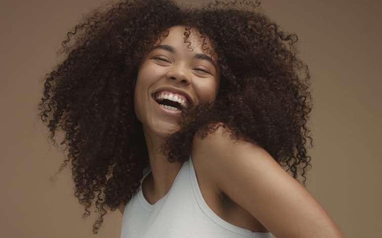 Mulher de cabelo cacheado sorrindo