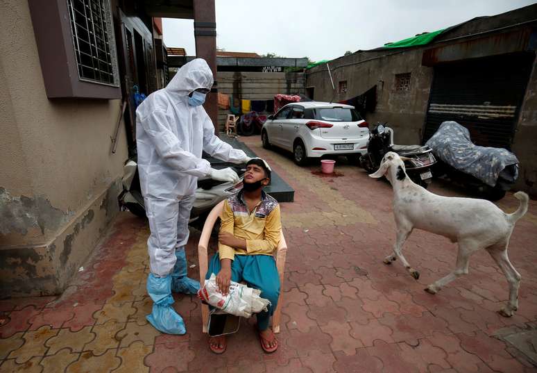 Profissional médico, utilizando equipamentos de proteção, testa um garoto para o coronavírus na Índia. 24/07/2020. REUTERS/Amit Dave. 

