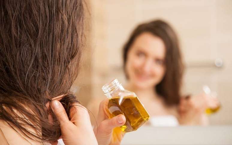 Mulher hidratando o cabelo com óleos naturais