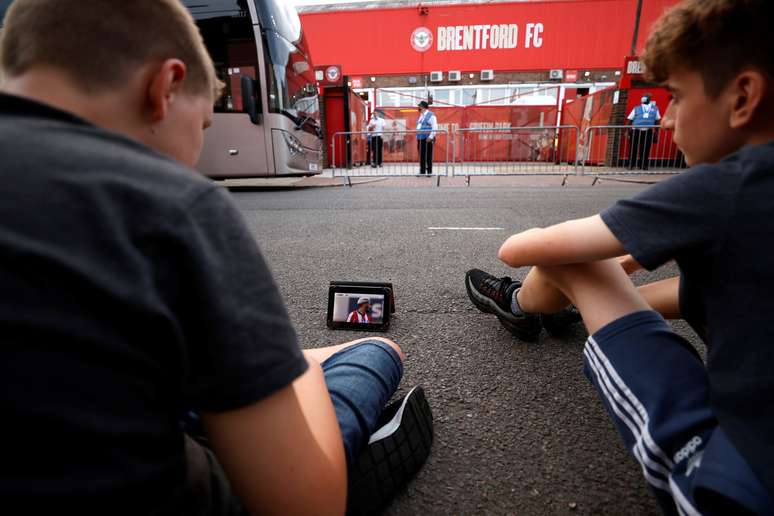 Torcedores assistem em um tablet semifinal da segunda divis&atilde;o inglesa entre Brentford e Swansea do lado de fora do est&aacute;dio Griffin Park, do Brentford 
29/07/2020
Action Images via Reuters/John Sibley