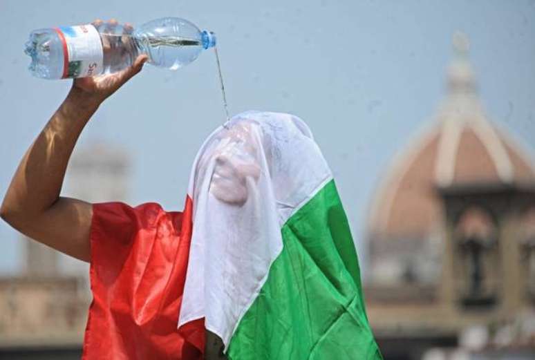 Mulher com bandeira da Itália se refresca do calor em Florença, em foto de arquivo