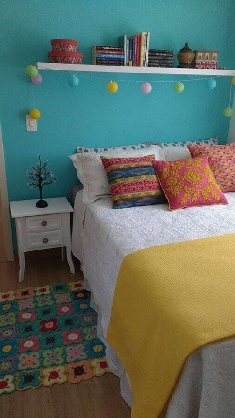 33. Quarto simples decorado com parede azul, almofadas coloridas e mesa de cabeceira com gavetas brancas &ndash; Foto: Pinterest