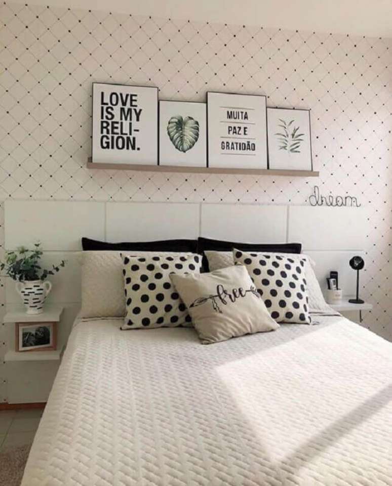 61. Almofadas para cama de casal em quarto todo branco com papel de parede delicado e prateleira para quadros sobre a cabeceira – Foto: Pinterset