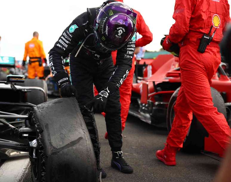 Lewis Hamilton olha o pneu dianteiro esquerdo furado que quase custou a vitória em Silverstone 