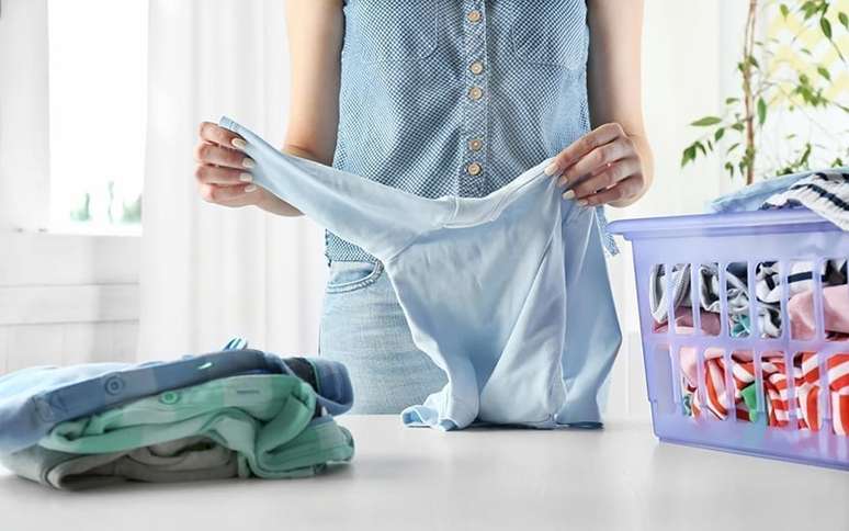 Mulher segurando uma peça de roupa em uma lavanderia