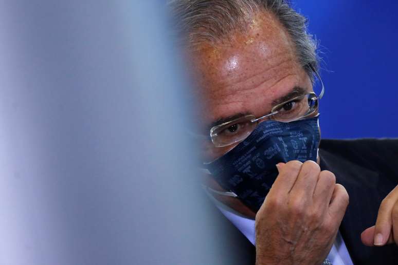 Brazil's Economy Minister Paulo Guedes adjusts his protective face mask before the inauguration ceremony of the new Communications Minister Fabio Faria (not pictured) at the Planalto Palace, in Brasilia, Brazil June 17, 2020. REUTERS/Adriano Machado