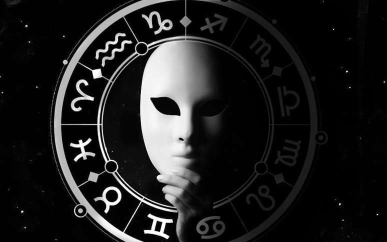 Máscara branca com fundo preto e, ao redor, os símbolos dos signos