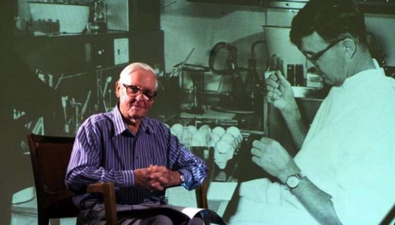 O professor Frank Fenner em frente a uma foto projetada de si mesmo, tirada na década de 1950