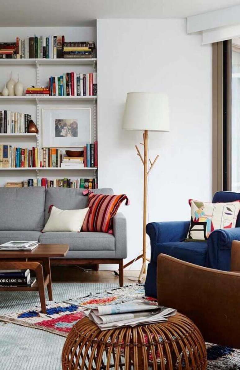 14. Decoração de sala de estar com prateleira para livros e abajur de chão madeira ao lado de sofá – Foto: Apartment Therapy