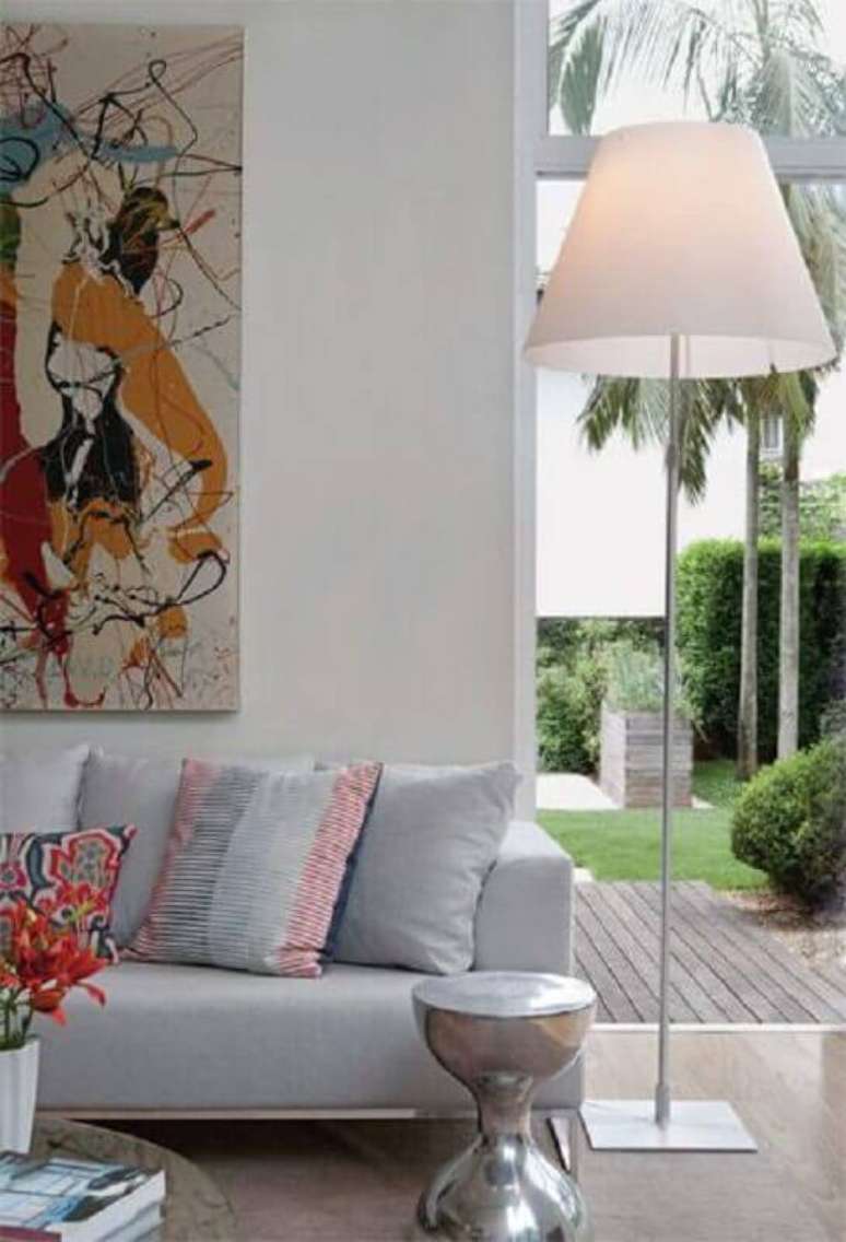 16. Abajur de chão para sala decorada com quadro grande colorido e sofá cinza claro – Foto: Pinterest