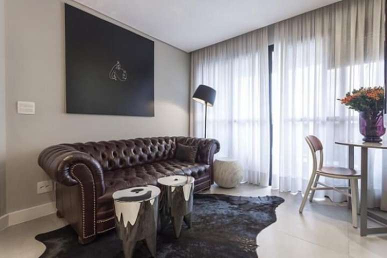 73. Abajur de chão “torto” para sala de estar decorada com sofá chesterfield e tapete preto. Projeto de Mauricio Karam