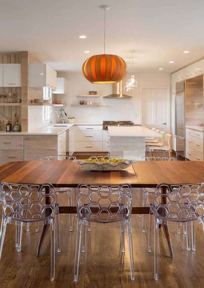 13. Sala de jantar integrada com cozinha branca planejada com mesa com cadeiras transparentes – Foto: Constance Zahn