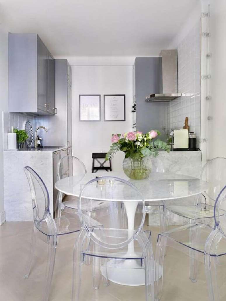 38. Cozinha integrada com sala de jantar toda branca decorada com mesa redonda e cadeira ghost transparente – Foto: Apartment Therapy