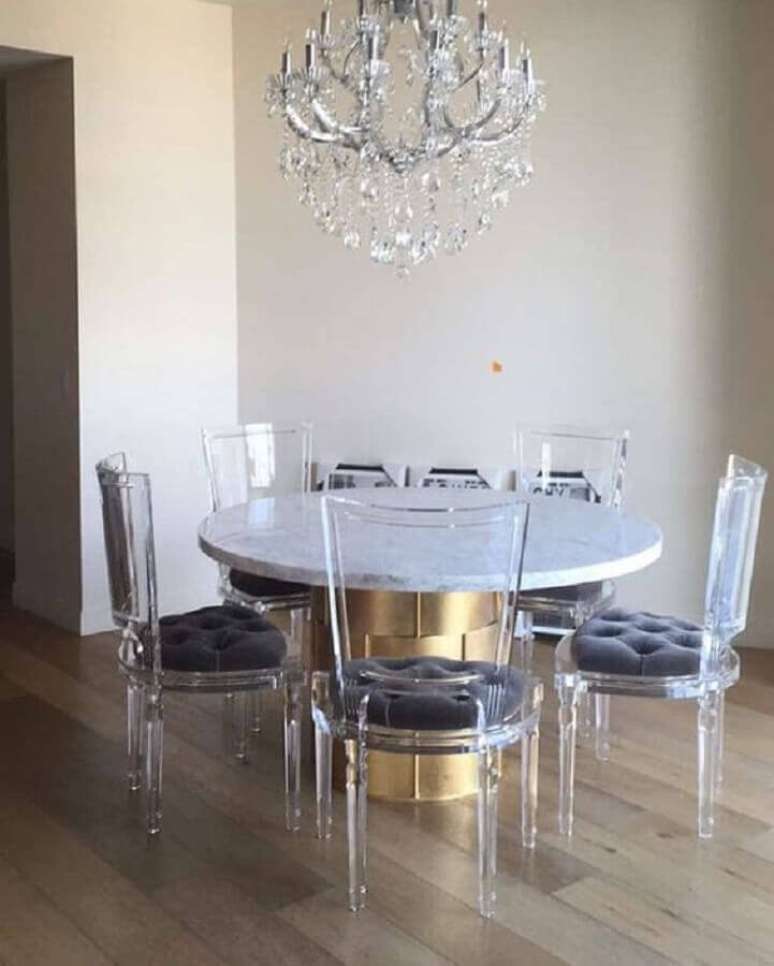 50. Mesa com cadeiras transparentes para sala de jantar com lustre de cristal – Foto: Curated Interior
