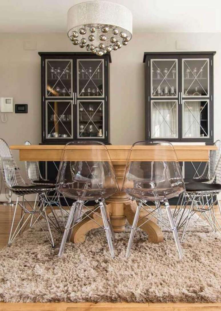 52. Sala de jantar decorada com cristaleira preta, mesa de madeira redonda e cadeira eames transparente – Foto: Best Home Decor
