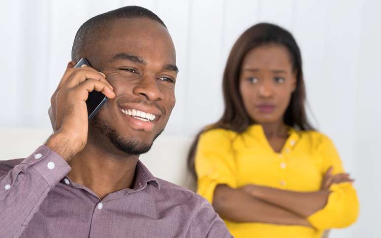 Homem falando no celular e mulher desconfiada