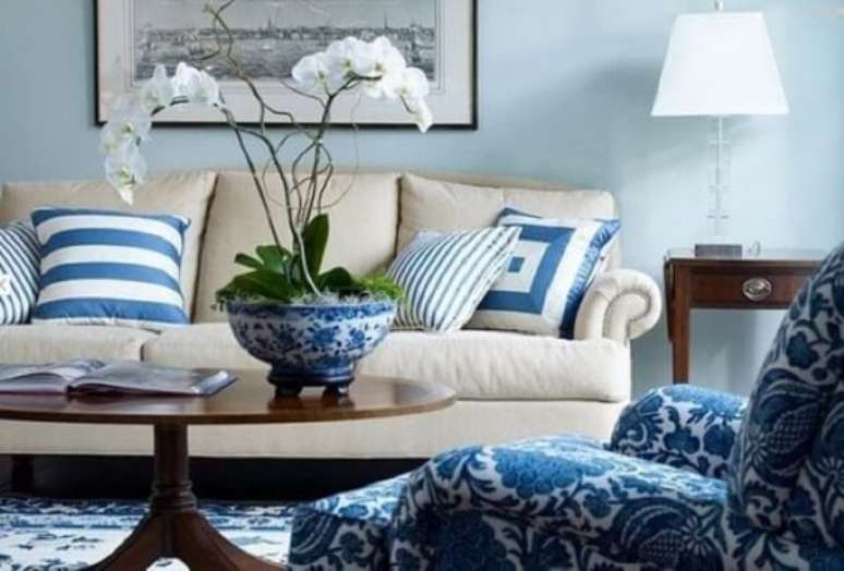 27- As plantas para sala delicadas como as orqu&iacute;deas s&atilde;o plantadas em vaso de lou&ccedil;a nas mesmas cores da poltrona e almofadas. Fonte: Vai com Tudo