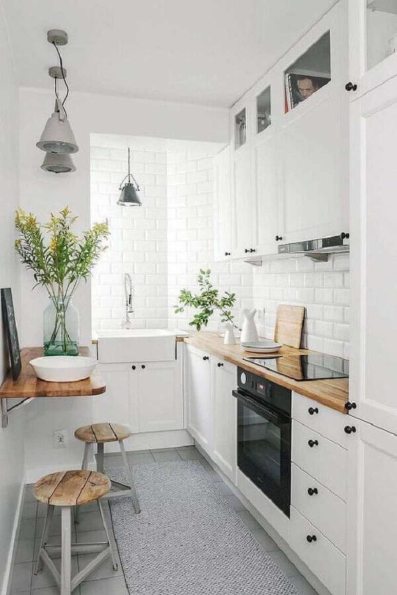 36. Modelo de cozinha pequena sob medida super charmosa com armários brancos e bancada de madeira – Foto: Apartment Therapy