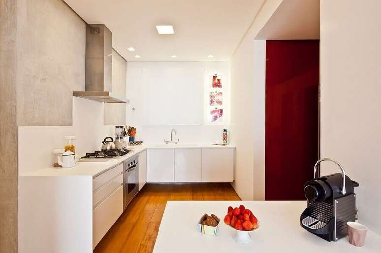 59. Cozinha sob medida de canto planejada com armários brancos e parede de cimento queimado – Foto: A.M Studio Arquitetura