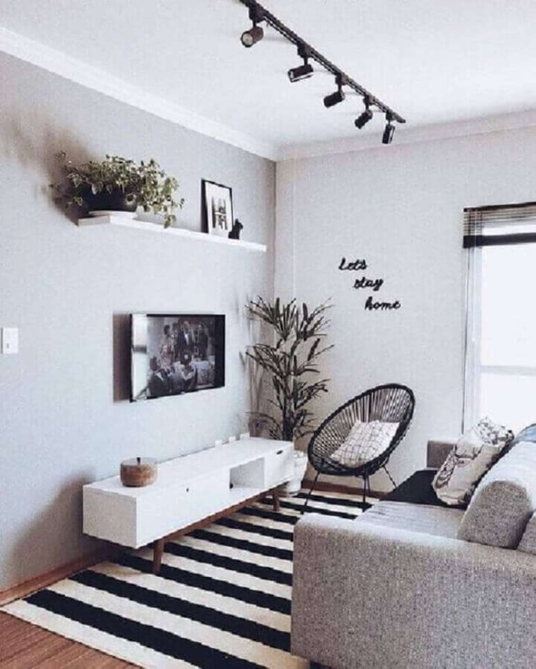 13. Decoração simples para sala cinza e branca com tapete listrado e TV direto na parede – Foto: Pinterest