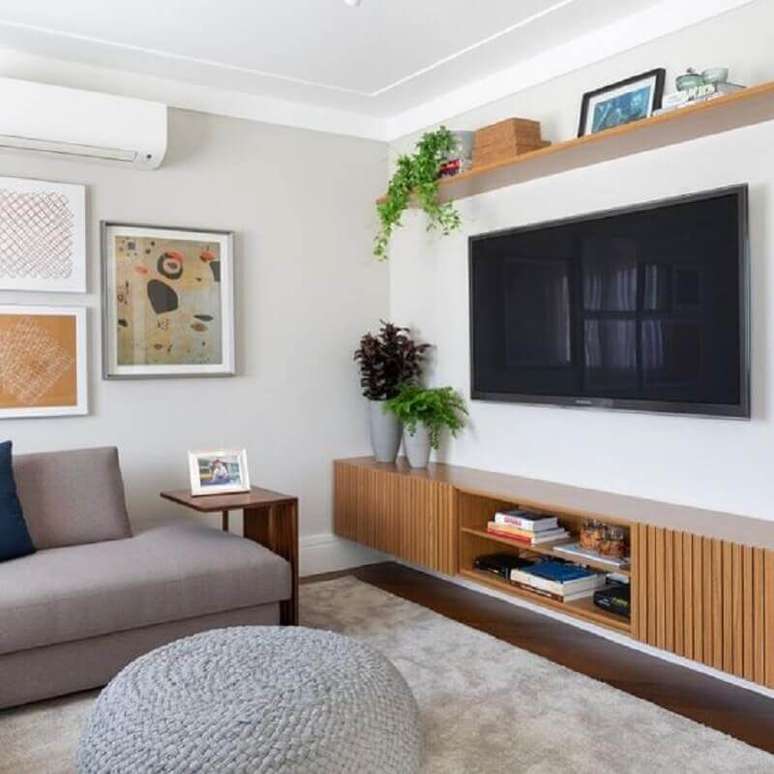 31. TV direto na parede de sala de estar com rack de madeira suspenso – Foto: Jeito de Casa